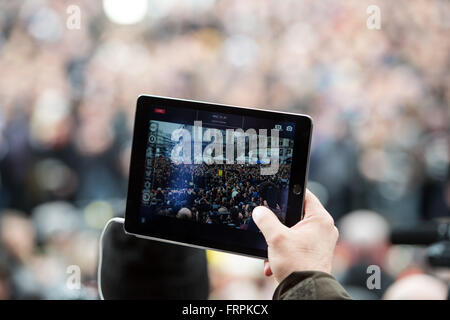 Bruxelles, Belgique. Mar 23, 2016. Un homme utilise son ordinateur tablette pour prendre une photo des nombreuses personnes qui se sont réunis pour observer une minute de silence en face de la bourse, Place de la Bourse à Bruxelles, Belgique, 23 mars 2016. Au moins 30 personnes ont été tuées et plus de 180 ont été blessées lors d'une nouvelle série d'attaques terroristes qui ont secoué Bruxelles, Belgique, le 22 mars 2016. Photo : FEDERICO GAMBARINI/dpa/Alamy Live News Banque D'Images