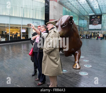 Deux femmes et un homme de prendre une photo par le taureau selfies à Birmingham Bullring, England, UK Banque D'Images