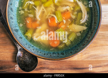 Soupe au poulet fait maison dans un bol turquoise avec un cuillère. Banque D'Images