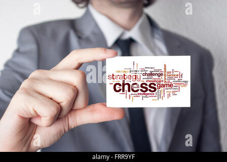 Les échecs. Homme d'affaires en costume avec une cravate noire montrant ou holding business card Banque D'Images