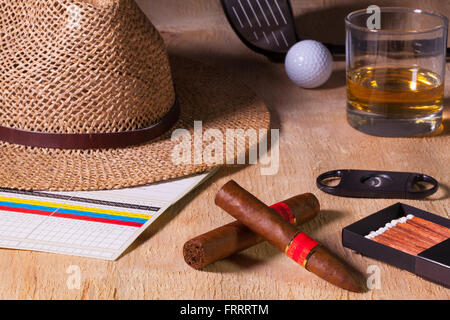 Siesta - cigare, chapeau de paille,whisky écossais et le golf conducteur sur une table en bois Banque D'Images