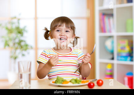 Heureux l'enfant fille manger des légumes. Une alimentation saine pour les enfants Banque D'Images