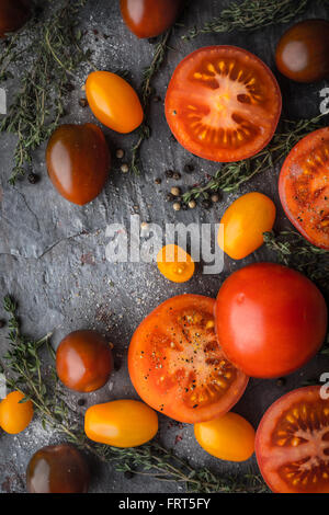 Mélanger les tomates avec des herbes sur la table de pierre à la verticale Banque D'Images