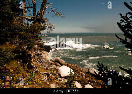 Le temps au loin s'approche du rivage rayé à mesure que les vagues s'écraseront contre la côte rocheuse. Banque D'Images