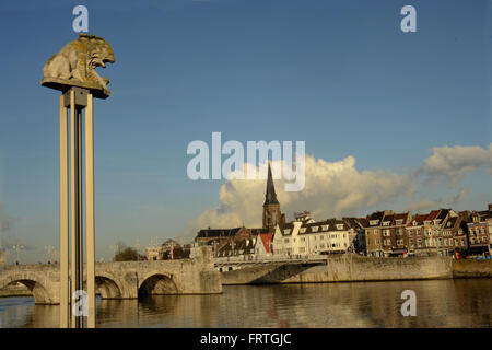 Petit lion sur socle à côté de Meuse à Maastricht. Sint Servatius et pont St Martins en arrière-plan. Banque D'Images