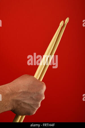 Man main tenant deux baguettes en bois sur fond rouge, Close up Banque D'Images