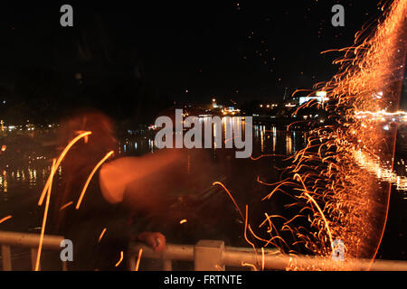 Une femme jette un bambou traditionnel feu d'artifice d'un pont au cours de festivités Loy Krathong dans Chiang Mai, Thaïlande. Banque D'Images