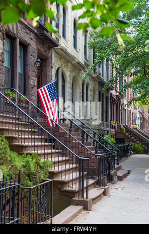 Escalier avec un drapeau américain par les maisons brownstone dans quartier résidentiel urbain de Brooklyn, NYC Banque D'Images