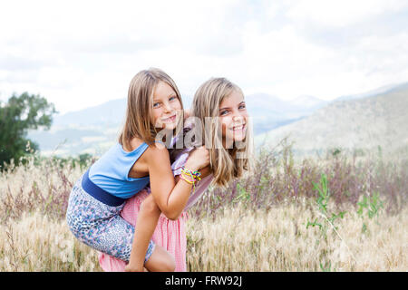 Espagne, Girona, portrait de deux sœurs heureux jouant sur un pré Banque D'Images