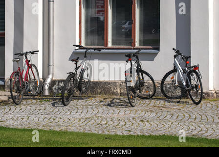 Quatre vélos garés à côté d'un mur gris sur le trottoir et pavées de la vieille ville de Porvoo en Finlande. Banque D'Images