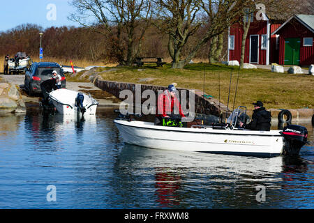 Torhamn, Suède - 18 mars 2016 : le lancement d'un petit bateau à moteur en plastique une rampe dans la marina. Un autre bateau dur en en Banque D'Images