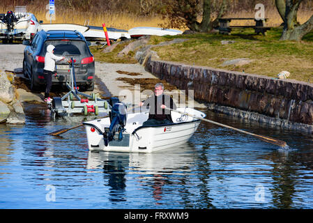 Torhamn, Suède - 18 mars 2016 : le lancement d'un petit bateau à moteur en plastique une rampe dans la marina. Bateau est ramé 23-08-2003 par l'homme Banque D'Images