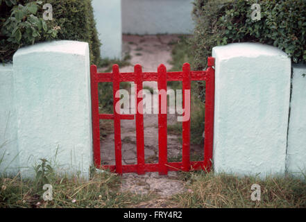 Close-up of a red painted metal gate dans mur blanc Banque D'Images