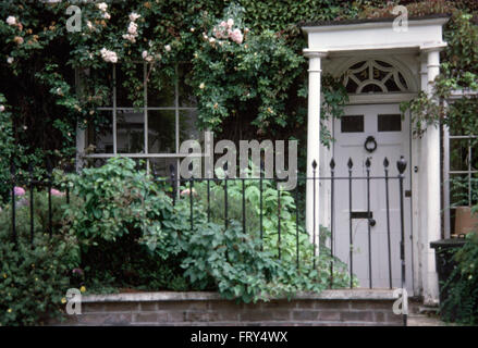 En fer forgé sur le jardin de devant d'une maison de ville avec véranda et porte avant blanc Banque D'Images