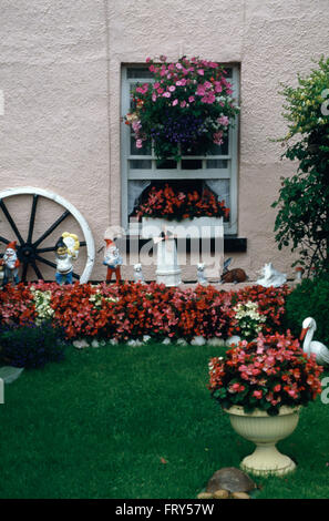 Les couleurs vives et les nains de jardin dans la banlieue de jardin à l'avant d'une maison rose avec 70 murs Pebble Dash Banque D'Images