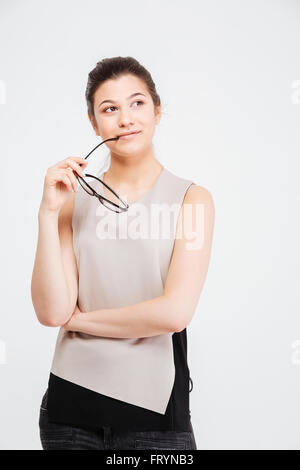 Smiling pretty young woman holding glasses et rêver sur fond blanc Banque D'Images