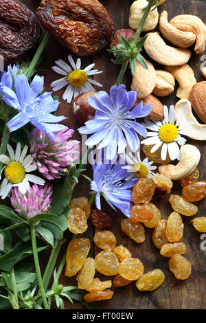 Les fruits séchés et les noix près de fleurs sauvages sur planche de bois Banque D'Images