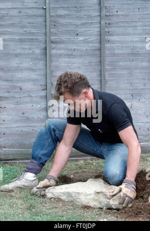 Positionnement jardinier d'un grand rocher dans une nouvelle rocaille salon pour un usage éditorial uniquement Banque D'Images