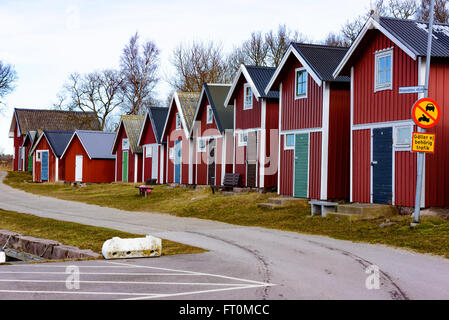 Torhamn, Suède - 18 mars 2016 : la suite de rouge et blanc cabanes de pêche en bois le long d'une petite route étroite. Ces cabanes sont typ Banque D'Images