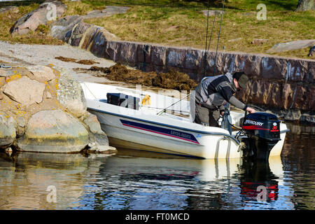 Torhamn, Suède - 18 mars 2016 : une personne se situent dans un bateau ouvert penché sur le moteur et contrôler le niveau de gaz avant Banque D'Images