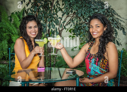 2 jeunes femmes hispaniques toast avec un verre de margarita sur patio tropical - Puerto Vallarta, Mexique # 613PV Banque D'Images