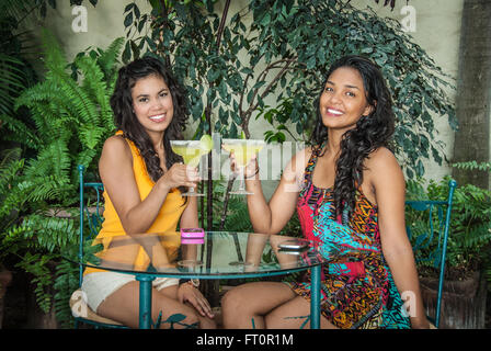 2 jeunes femmes hispaniques toast avec un verre de margarita dans patio tropical - Puerto Vallarta, Mexique # 613PV Banque D'Images