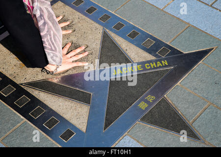 Femme de placer ses mains dans les empreintes de la star de cinéma de Jackie Chan sur l'Avenue of Stars, promenade le long de front de mer du port de Hong Kong, Tsim Sha Tsui, Kowloon, Hong Kong Banque D'Images