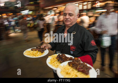 Waiter serving Steak et frites, type Parilla restaurant, Mercado del Puerto, Montevideo, Montevideo, Uruguay Banque D'Images
