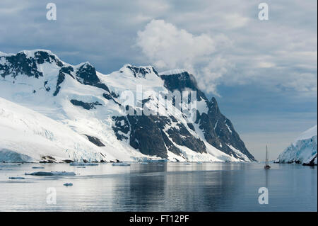 Un bateau à voile et des montagnes neige-couvertes, Lemaire Channel, près de la Terre de Graham l'Antarctique Banque D'Images