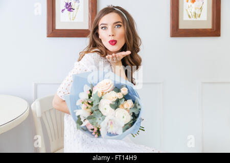 Lovely Cute young woman holding bouquet de fleurs et l'envoi d'un baiser Banque D'Images