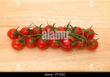 Tomates mûries sur vigne sur une planche en bois Banque D'Images