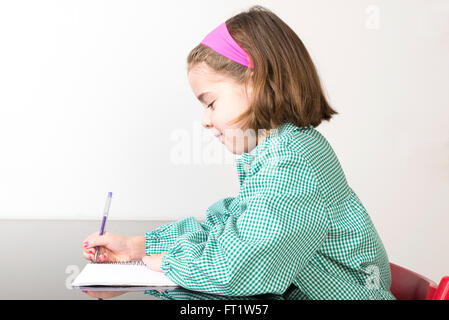 Petite fille avec un plaid vert smock écrit dans un ordinateur portable à la maison Banque D'Images