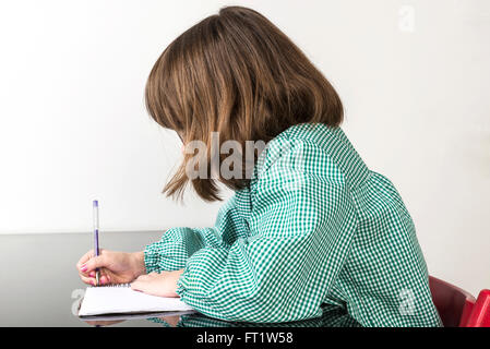 Petite fille avec un plaid vert smock écrit dans un ordinateur portable à la maison Banque D'Images