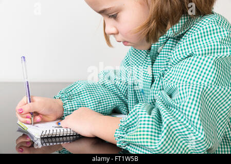 Petite fille avec un plaid vert smock l'écriture et le dessin dans un ordinateur portable à la maison Banque D'Images