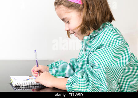 Petite fille avec un plaid vert smock l'écriture et le dessin dans un ordinateur portable à la maison Banque D'Images