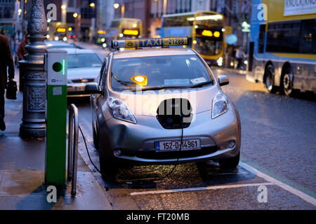 Voiture Nissan Leaf taxi électrique branché pour recharger à charge sur une rue de Dublin, Irlande, Europe Banque D'Images