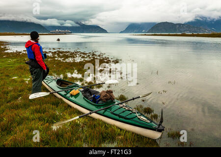 Un kayakiste regardant un bateau de croisière de passage à Glacier Bay National Park, Alaska Banque D'Images