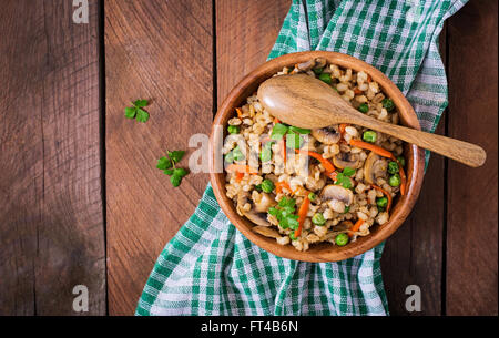 L'orge perlé friable végétarienne du porridge aux champignons et petits pois dans un bol en bois. Vue d'en haut Banque D'Images