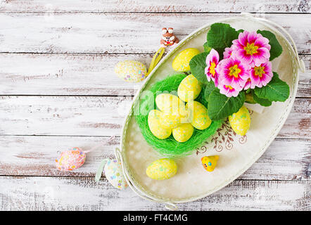 Oeufs de Pâques et de fleurs sur un fond en bois clair. Vue d'en haut Banque D'Images