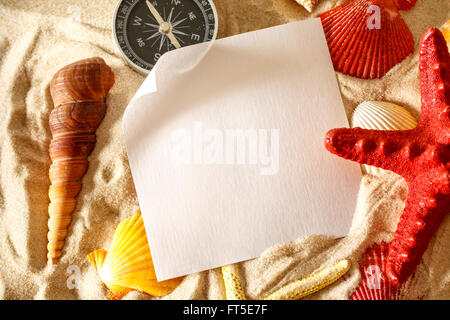 Les coquillages, boussole et le papier blanc sur le sable Banque D'Images