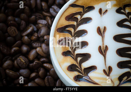 Libre d'une belle tasse de café latte art sur fond de haricots Banque D'Images