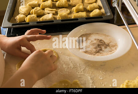Les mains des enfants de prendre une forme de pâte à biscuit sur la table de cuisine Banque D'Images
