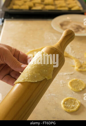 La main avec roulement-pin, de la pâte à cookies sur la table de cuisine Banque D'Images