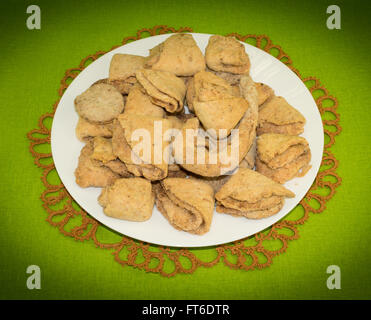 Le fromage cottage cookies à la cannelle dans une assiette blanche avec frivolité dentelle sur fond vert Banque D'Images