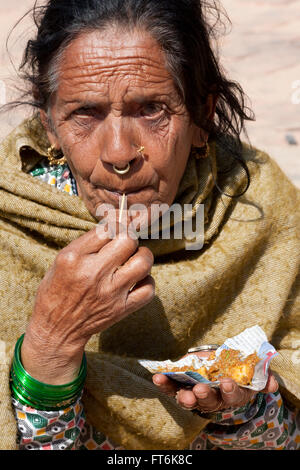 Népal, Katmandou. Vieille Femme avec anneau dans le nez et le nez de broche, de manger. Banque D'Images