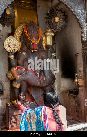 Népal, Katmandou. Femme présentant des offrandes à Narsingha Statue, Vishnu dans son incarnation de l'homme-lion. Banque D'Images