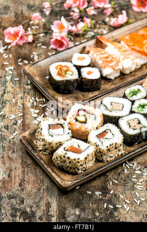 Sushi, maki, sashimi et sushi rolls sur fond de bois avec des fleurs de printemps. Tons style vintage photo Banque D'Images