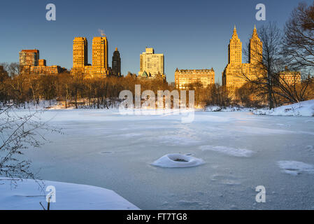 Lever du soleil d'hiver sur le lac gelé du Parc Central avec vue sur l'Upper West Side de Manhattan les bâtiments. New York City Banque D'Images