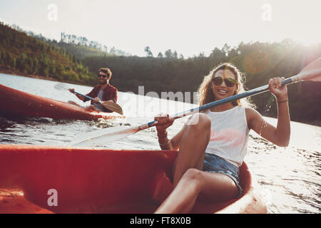 Belle jeune femme kayak dans un lac avec l'homme le canotage dans l'arrière-plan. Jeune couple canoë sur la journée d'été. Banque D'Images