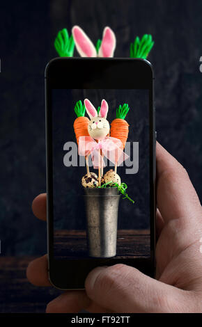 Man photographing carottes et bunny cake pops dans le métal verre sur fond de bois Banque D'Images